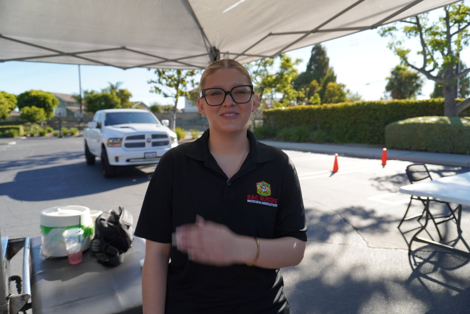 A member of the B&C crew in a company polo, working under the canopy at an outdoor event