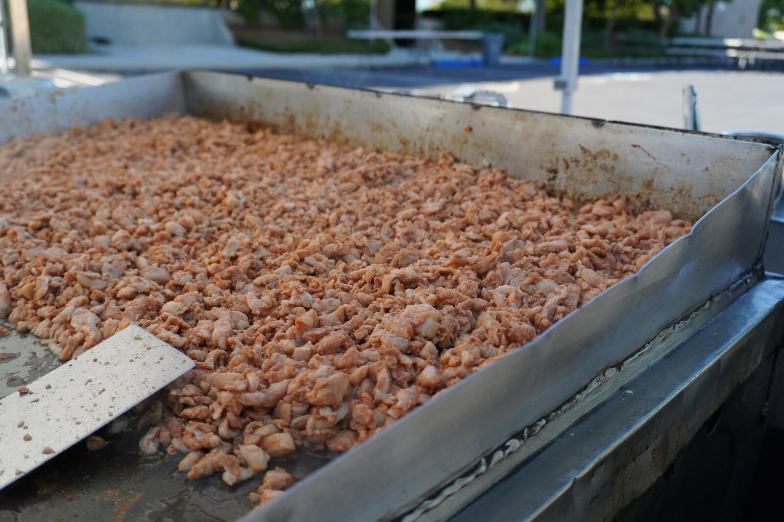 The cart griddle covered end to end with carne asada part-way through cooking