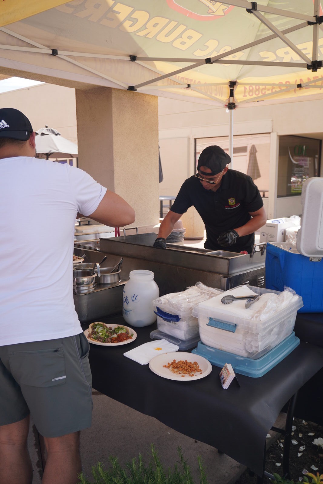 A guest being served a plate at the B&C Burgers cart under the branded canopy
