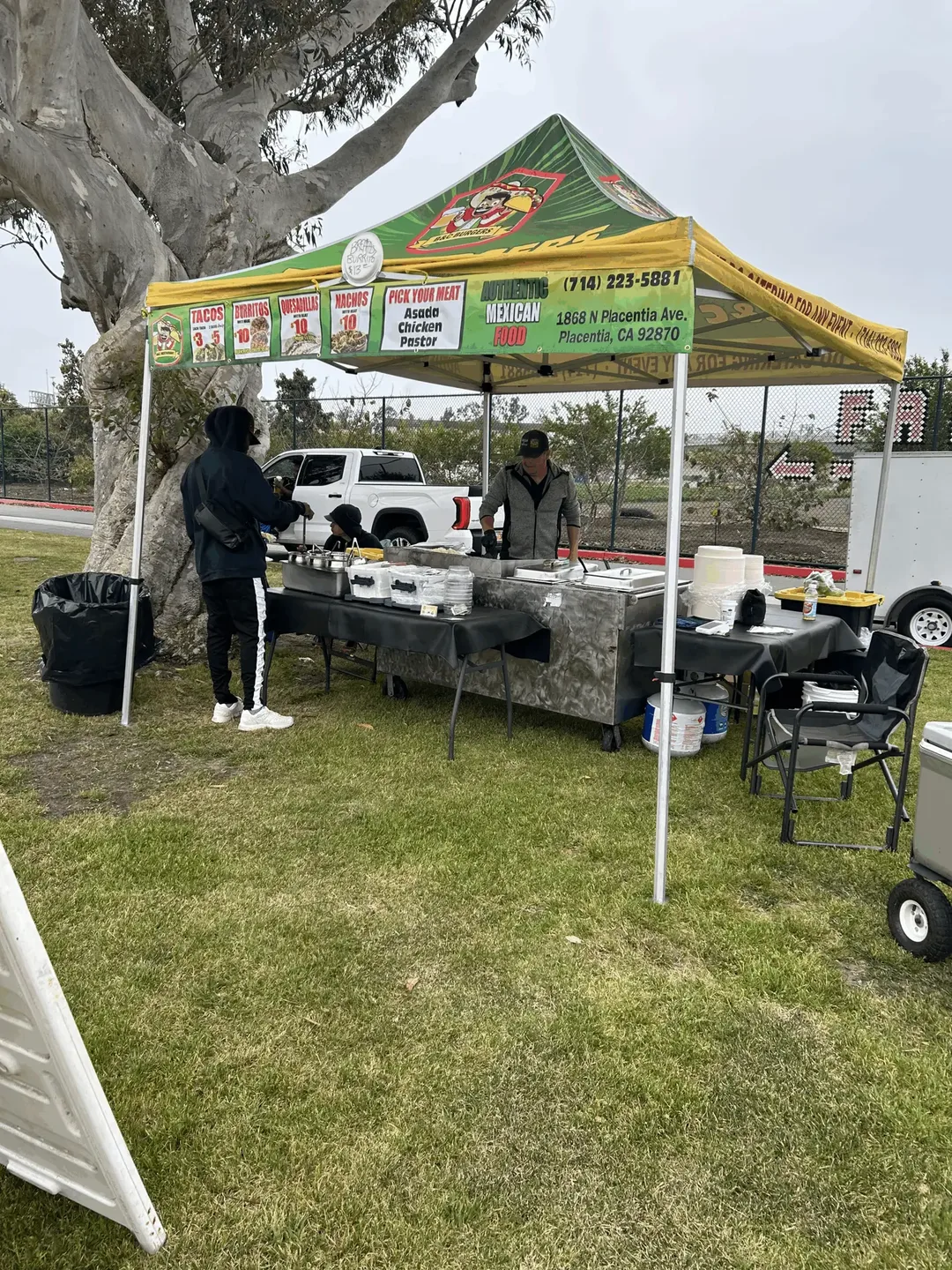 The taco cart set up on the grass under the green B&C canopy