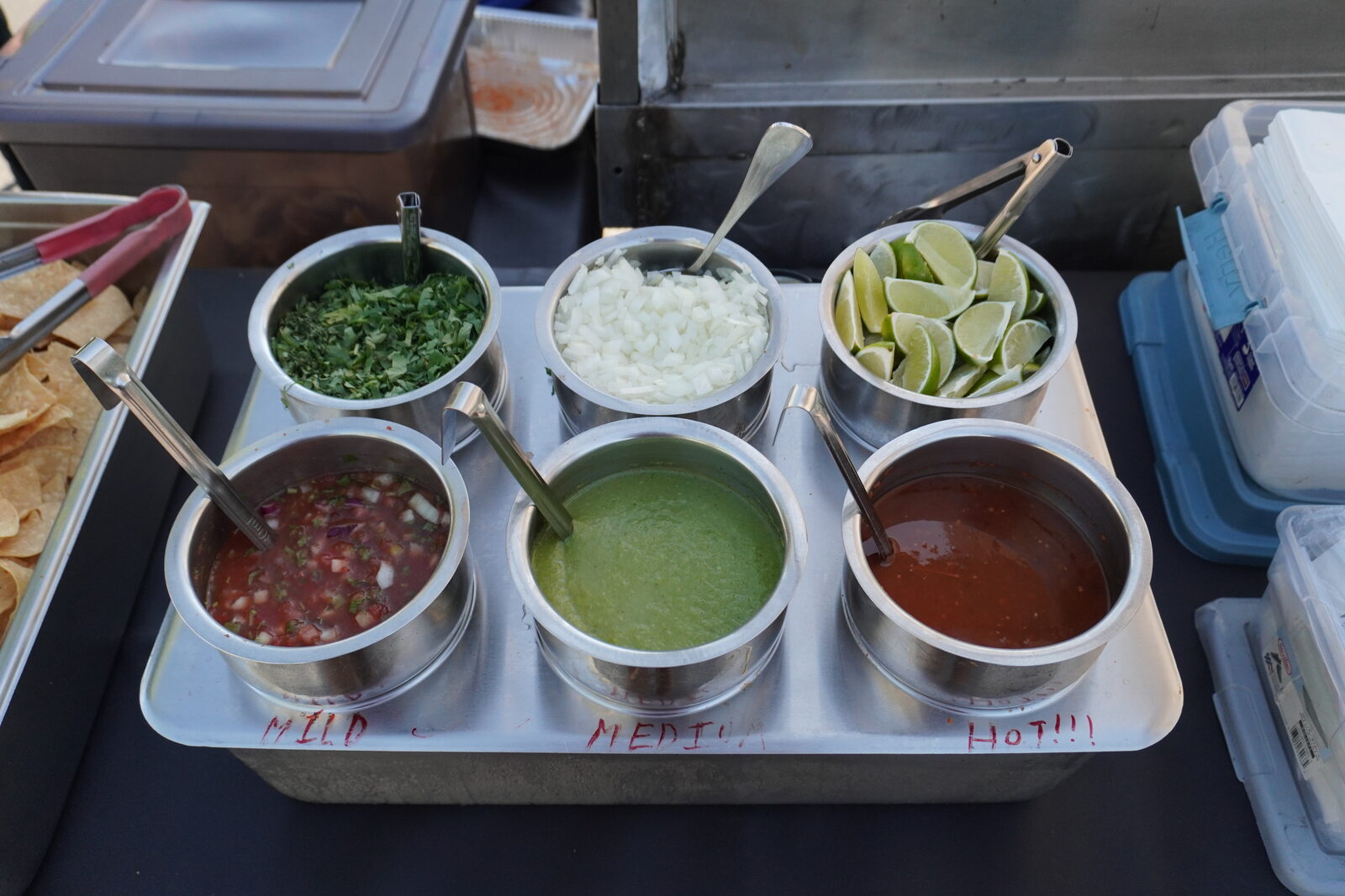 The salsa and toppings lineup laid out under the canopy