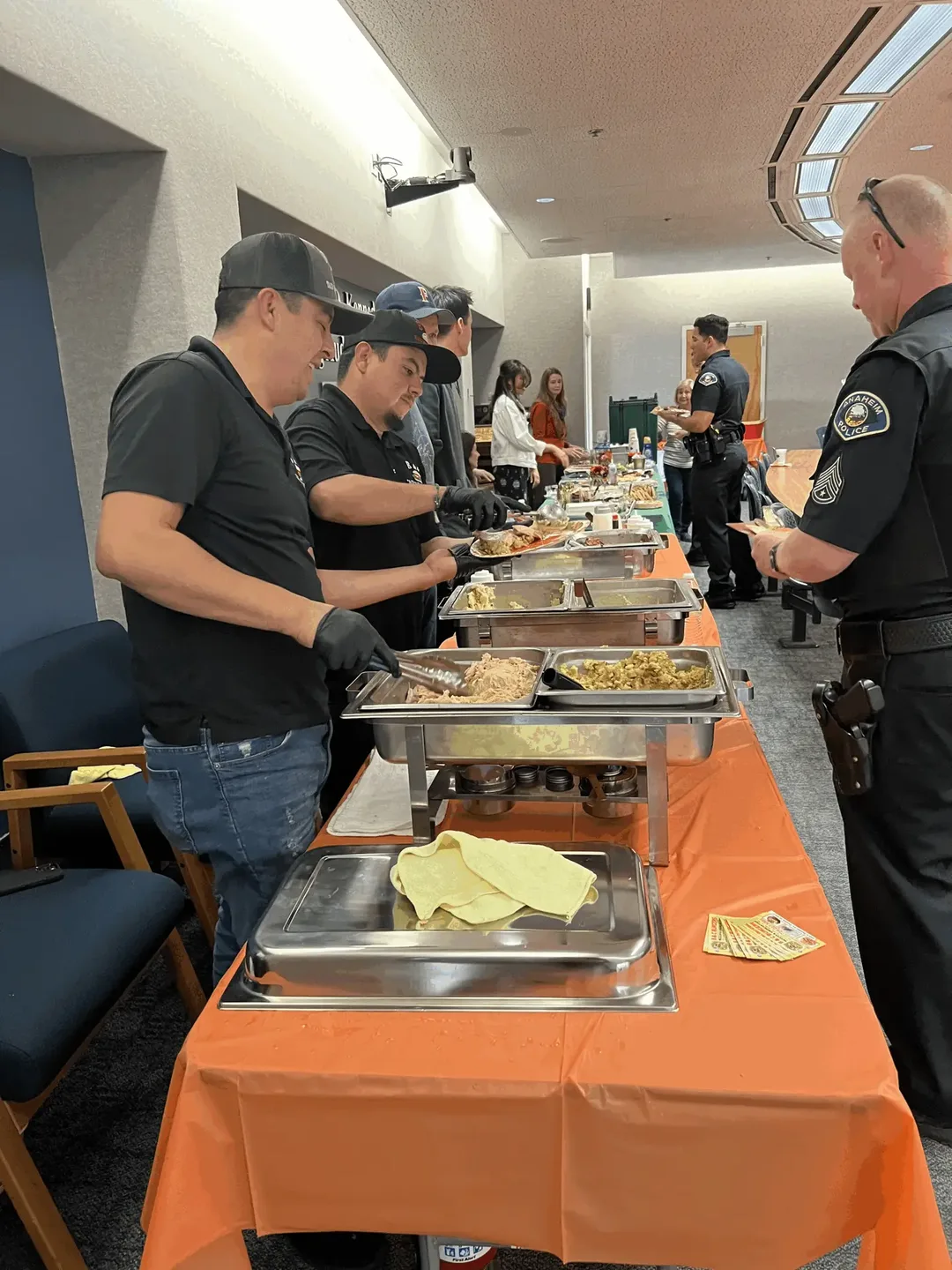 Carving and serving down a line of chafing dishes at an indoor lunch