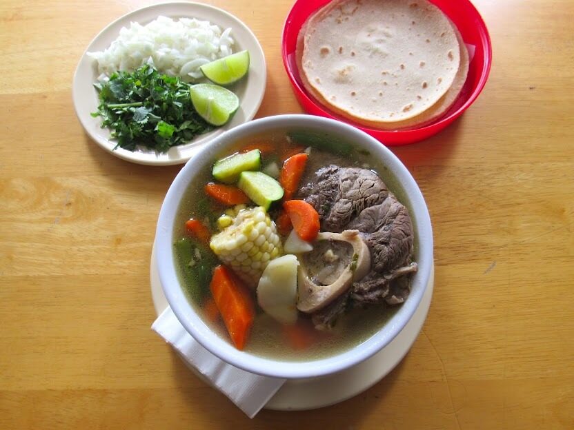 Bowl of caldo de res with beef, corn and vegetables in the broth