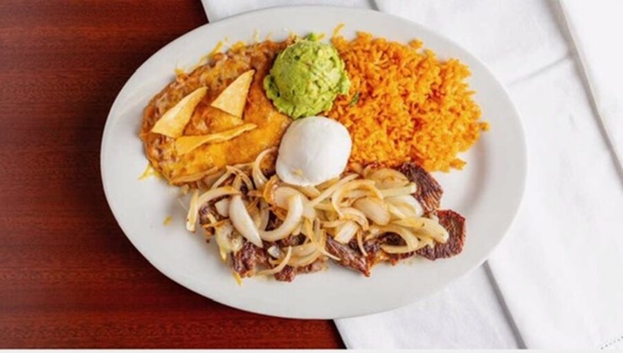 Carne asada plate with grilled onions, Spanish rice, refried beans and guacamole