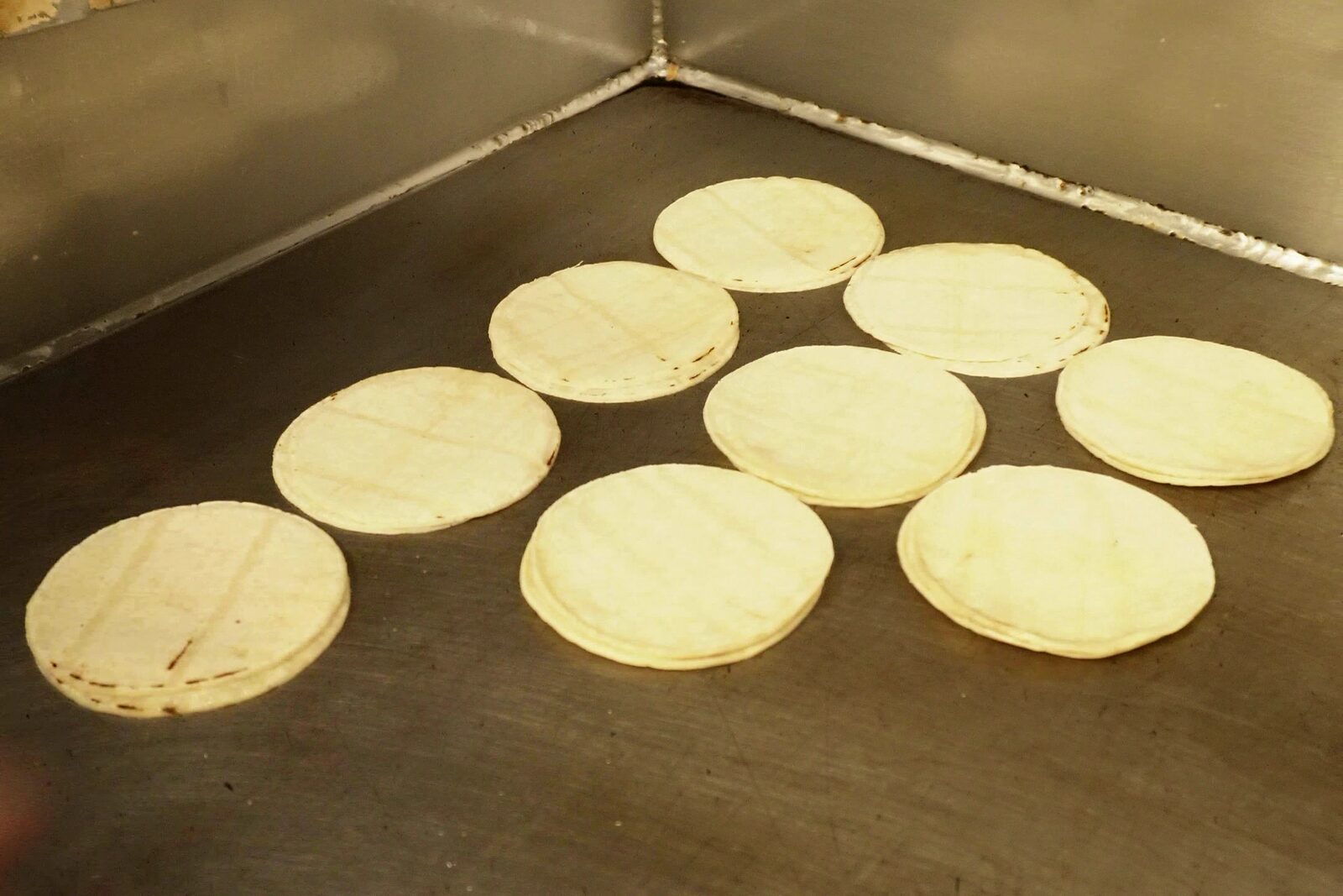 Corn tortillas warming in small stacks on the flat-top in our kitchen